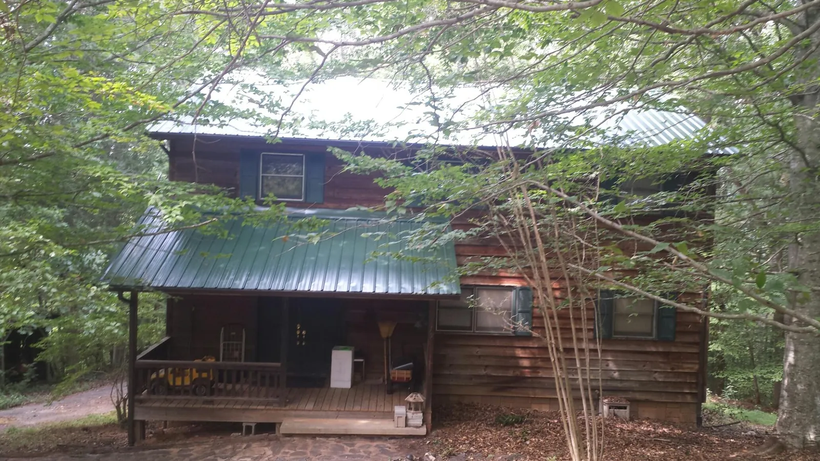 Green metal roof and covered porch on a log cabin in New Bedford