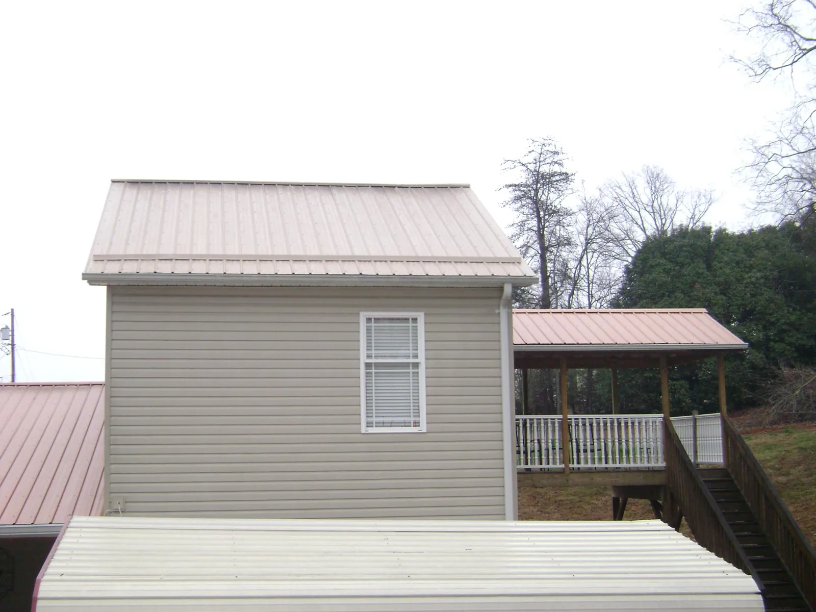 Tan metal roofs on a two story addition and attached porch, from a Roof Replacement job in New Bedford