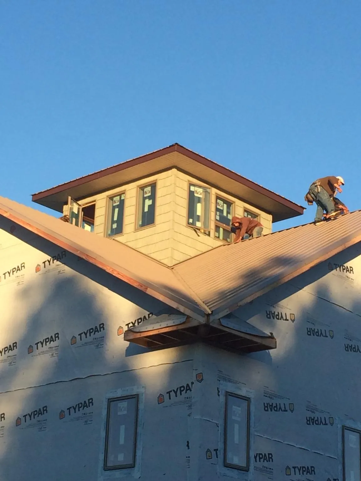 Roofers working around a rooftop cupola on a new metal roof at sunset — Roof Waterproofing in New Bedford by Roofing Brothers